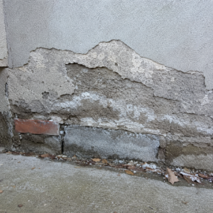 Moisture-damaged parging on a Toronto foundation wall with flaking and damp staining