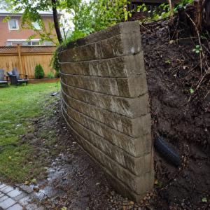 Leaning retaining wall showing outward movement from soil pressure.
