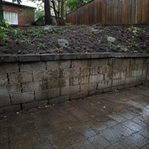 Masonry retaining wall with damp staining and early drainage problems.