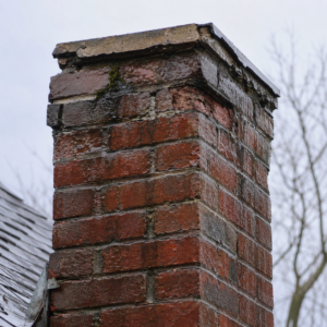 Water staining near chimney cap with early brick spalling.