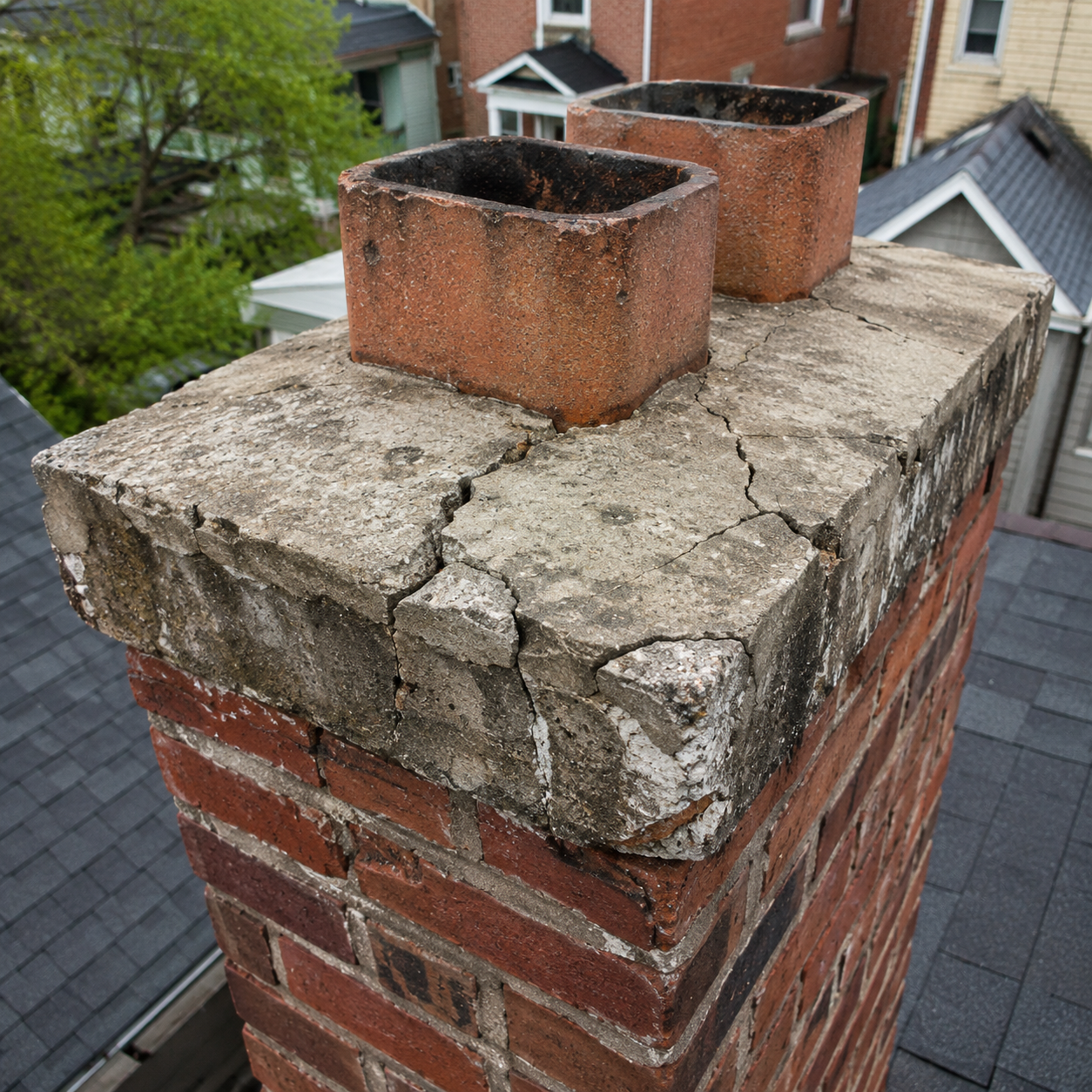 Damaged chimney crown with cracks and weathering.