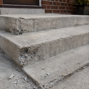 Concrete steps with chipped edges, cracks, and worn surface texture.
