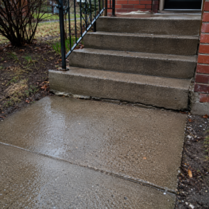 Concrete steps meeting a settled walkway with a small trip edge.